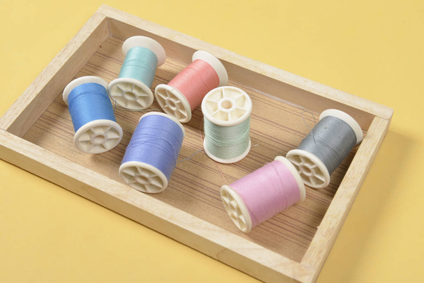 Flat lay of colored thread rolls for sewing on yellow background - Φωτογραφία, εικόνα