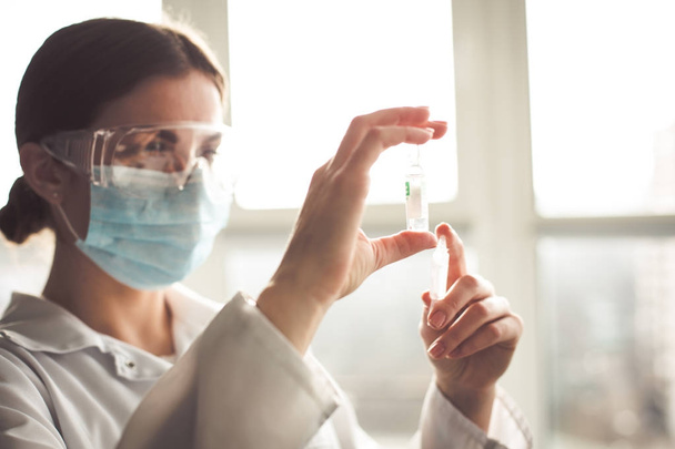 Laboratoriana mujer sosteniendo muestras de antibióticos y jeringa
 - Foto, imagen