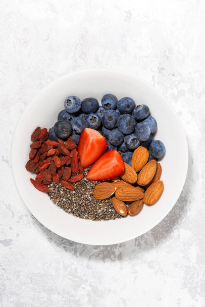 chia seeds, berries and nuts for a healthy breakfast, vertical - Photo, image