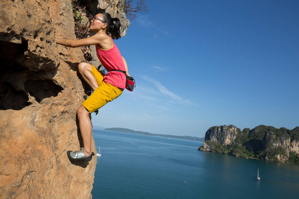 Γυναικεία ροκ ορειβάτης αναρρίχηση σε παραθαλάσσιο γκρεμό - Φωτογραφία, εικόνα