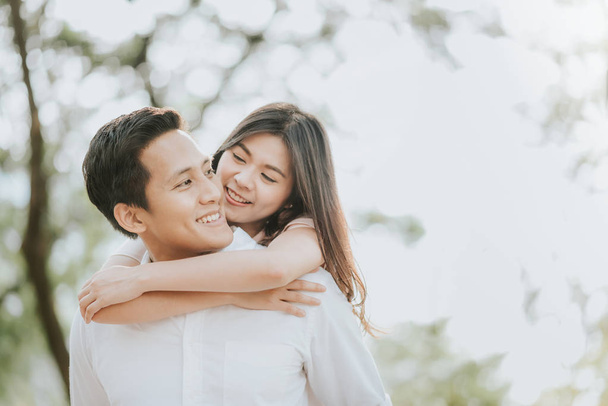 glückliches junges asiatisches verliebtes Paar, das eine gute Zeit hat und sich im Park umarmt - Foto, Bild
