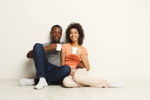 Smiling black couple wathing movie at home on the floor - Fotoğraf, Görsel