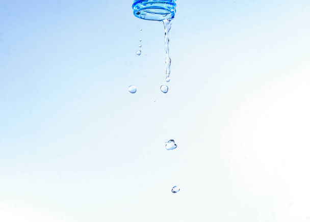 Fles te laten vallen met waterspatten geïsoleerd op een witte pagina - Foto, afbeelding