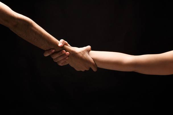 Τα χέρια του άνδρα και της γυναίκας στην αγάπη, απομονώνονται σε μαύρο - Φωτογραφία, εικόνα