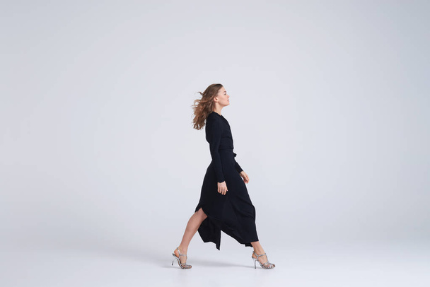 Vrouw model wandelen in trend zwarte jurk - Foto, afbeelding