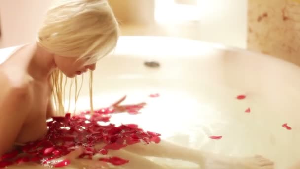 Una hermosa mujer sexy en un gran baño de hotel lleno de pétalos de rosa
 - Imágenes, Vídeo