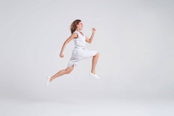 Сумасшедшая радостная девушка в летнем платье, прыгающая в одиночестве через бэкгру
 - Фото, изображение