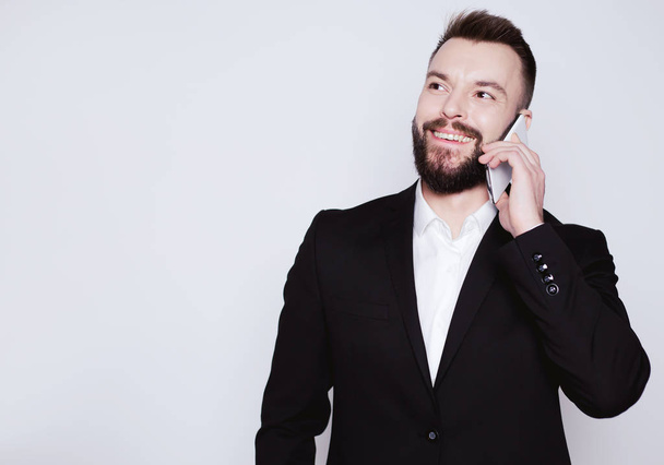 Hi, how are you? Handsome smiling elegant man talking on the phone with a friend on a white background. - Photo, image