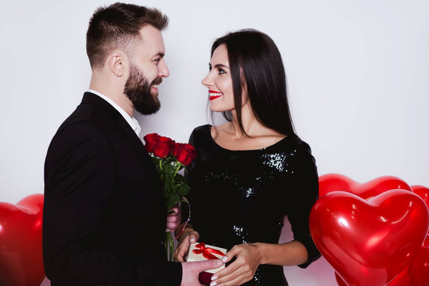 I congratulate you on the holiday of lovers. Smiling man giving flowers and gift to his happy woman on Valentine's Day. - Photo, Image