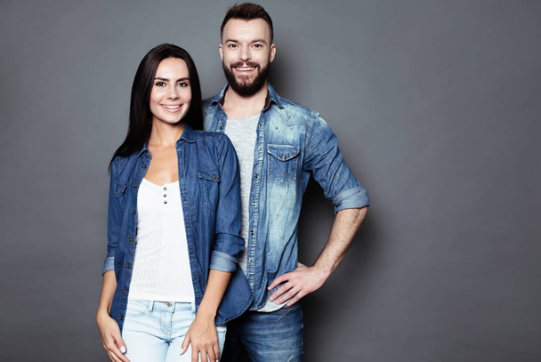Beautiful and happy young couple in love or family in casual wear having fun and making fun of each other and posing on a gray background isolated. - Fotó, kép