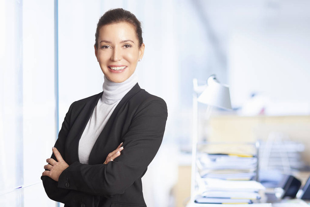 Chief financial officer businesswoman standing at the office while looking at camera and smiling.  - Photo, image