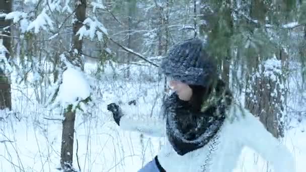 Funny playful girl throw snowball straight to camera, white splashes fly around. Fooling around in the snow and walks in the woods. Snow slowly fall down. - Footage, Video