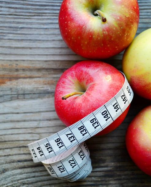 Concepto de dieta con manzanas rojas y amarillas y cinta métrica blanca en mesa de madera
 - Foto, imagen