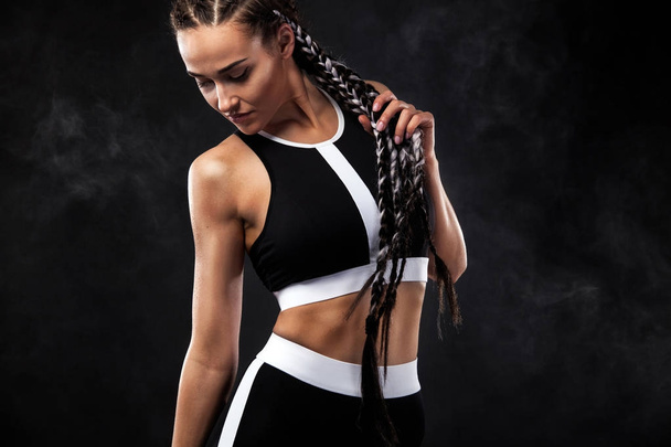 A strong athletic woman on black background wearing in black fashion sportswear, fitness and sport motivation. Sport concept with copy space. - Φωτογραφία, εικόνα