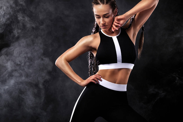 Сильная спортивная женщина на черном фоне, одетая в черную модную спортивную одежду, фитнес и спортивную мотивацию. Спортивная концепция с копировальным пространством
. - Фото, изображение