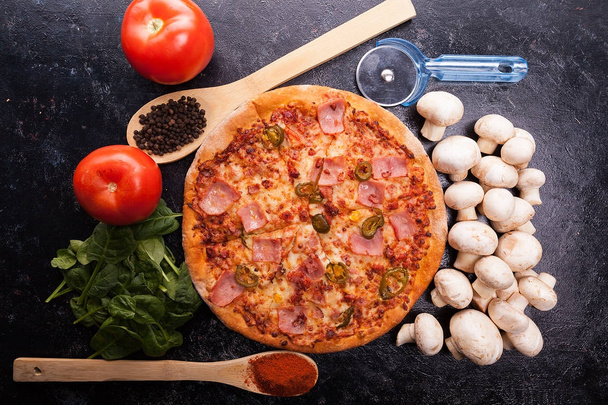 Top view on hot pizza next to ingredients which it is made of on - Foto, imagen
