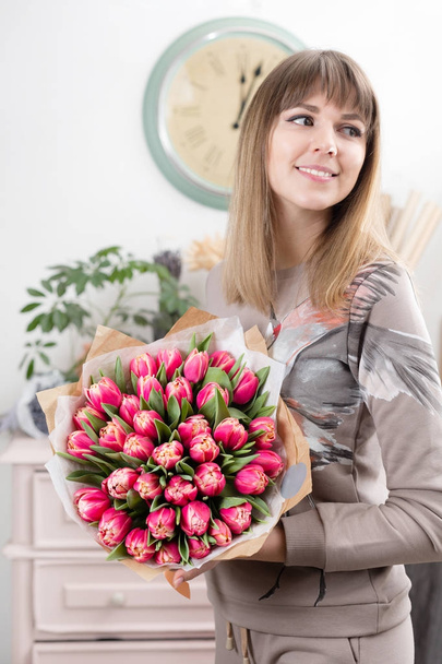 красивый роскошный букет розовых цветов тюльпанов в женской руке. работа флориста в цветочном магазине. милая милая девушка
 - Фото, изображение