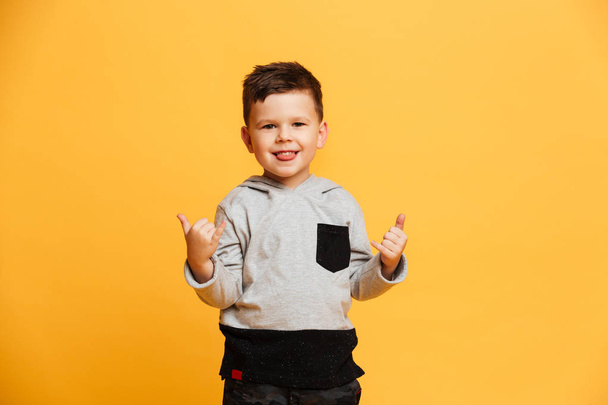 Cute boy child standing isolated over yellow - Фото, изображение