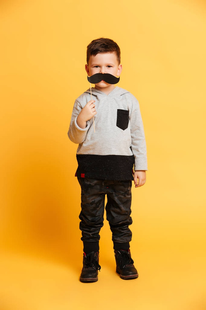 Cute little boy child holding fake moustache. - Fotoğraf, Görsel