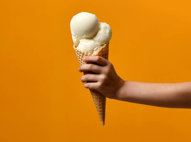 Fresh white ice cream waffles cone in kid hand  - Foto, afbeelding