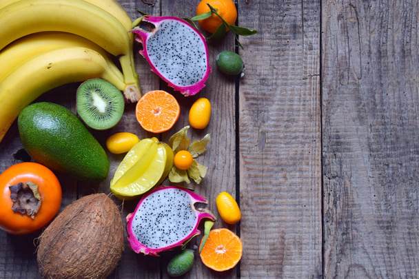 Mix van rijp tropisch fruit met avocado, mango, kokos, carambola's, banaan, kumquat, pitahaya's, kiwi. Superfood achtergrond. Vegetarische maaltijden. Kopiëren van ruimte - Foto, afbeelding