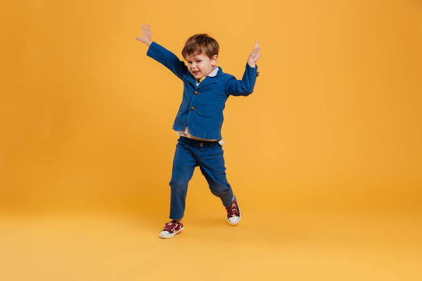 Funny little boy child standing isolated over yellow - Foto, Imagen