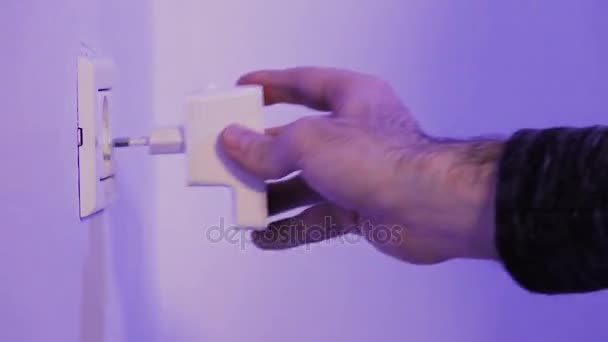 Man insert WiFi repeater into electrical socket on the wall and plug in a ethernet cable into it. The device help to extend wireless network in home or office. - Footage, Video