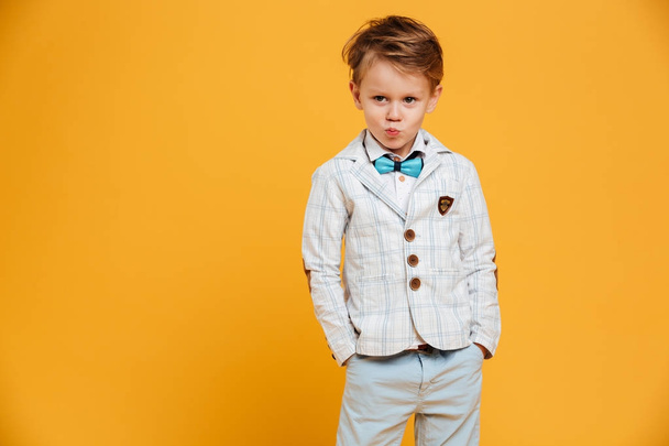 Cute little boy child standing isolated over yellow background - Foto, imagen