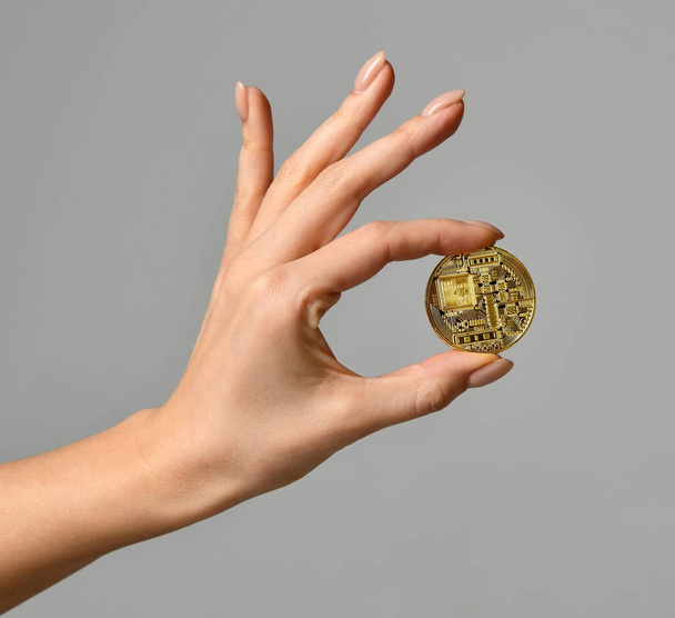 Hand hold gold bitcoin cryptocurrency on grey background. Digital currency back side - Foto, Imagen