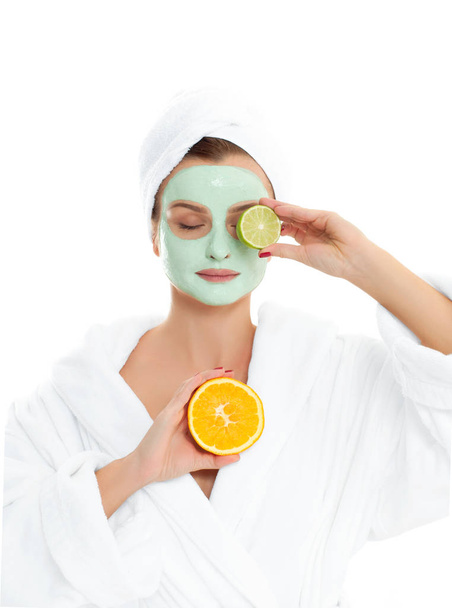 Beautiful woman is getting facial clay mask. Beauty, cosmetics, body care and spa concept - Foto, afbeelding