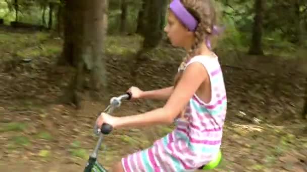 Hermosa joven está montando bicicleta a lo largo de caminos de asfalto en el bosque de verano
. - Metraje, vídeo