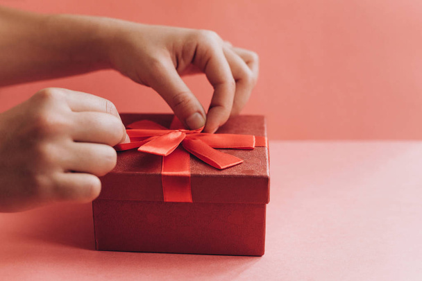 The girl has received a gift in a beautiful red box with a ribbon and is going to open it. - Zdjęcie, obraz