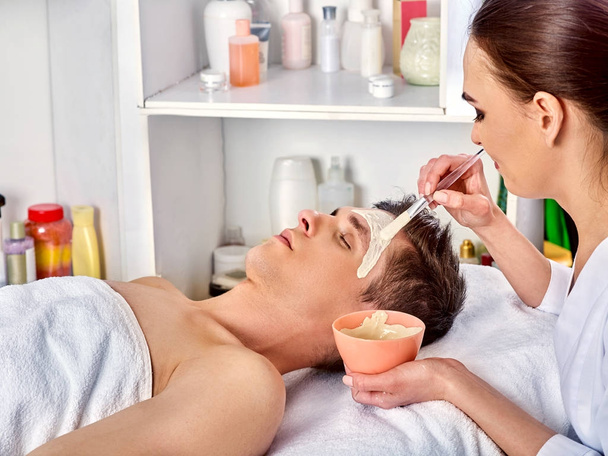 Mud facial mask of man in spa salon. Face massage . - Photo, Image