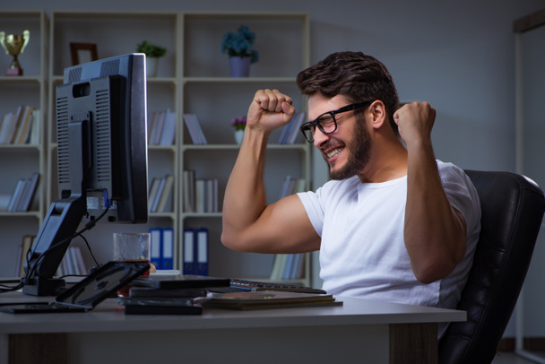 Young man staying late in office to do overtime work - Photo, Image