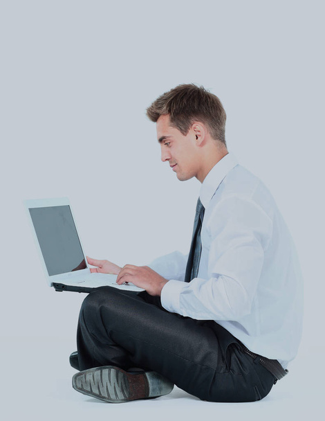 Isolated seated young businessman using a laptop - Photo, Image