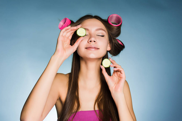 woman with curlers on her head holds a cucumber hand - Foto, Bild