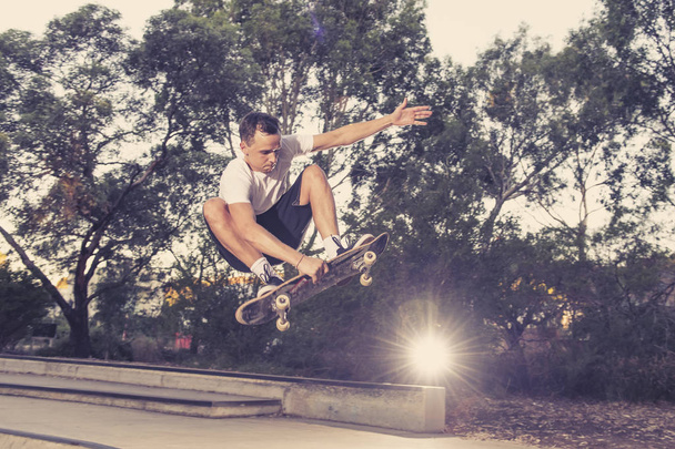 man practicing radical skate board jumping and enjoying tricks and stunts in concrete half pipe skating track in sport and healthy lifestyle  - Photo, Image