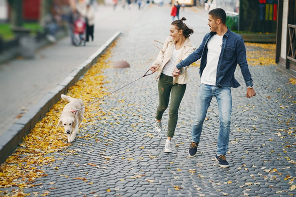 couple walking their dog on a sunny autumn day - Фото, изображение
