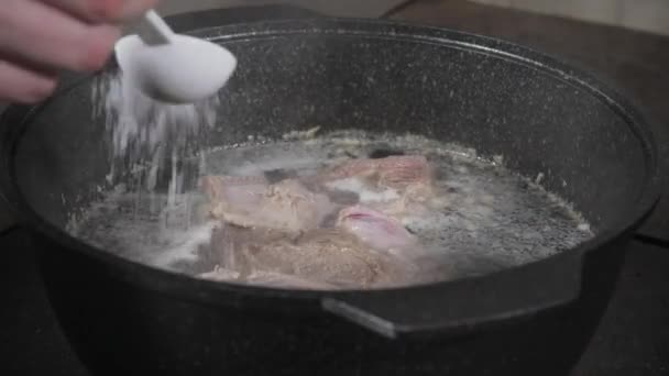 шеф-кухар готує сіль. традиційний яловичий бульйон з овочами, кістками та інгредієнтами в горщику, рецепт приготування. Суп у горщику для приготування їжі з соусом на фоні темного каменю. Вид зверху
 - Кадри, відео