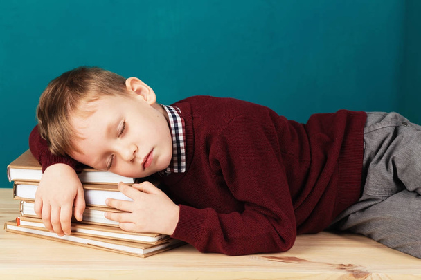 tired school boy asleep on books. little student sleeping on tex - 写真・画像