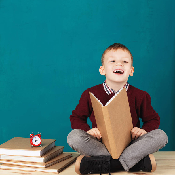Wesoły uśmiechający się mały chłopiec szkoły na biurku przed tur - Zdjęcie, obraz