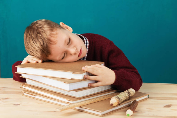 Уставший школьник спит на книгах. маленький студент спит на тексе
 - Фото, изображение