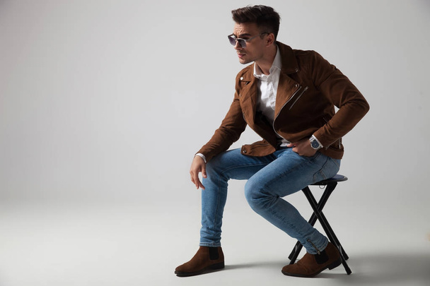 side view of a seated fashion model wearing sunglasses  - Foto, afbeelding