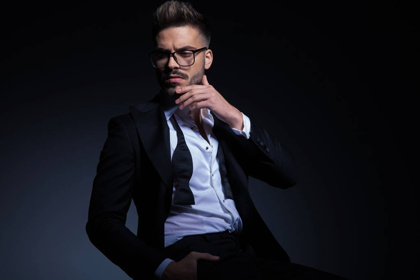 sexy young man wearing tuxedo and glasses is thinking - Foto, Imagem