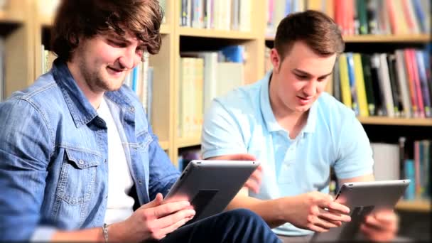 Hommes camarades de classe réseautage social sur tablettes dans la bibliothèque
 - Séquence, vidéo