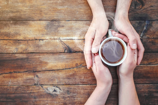 A cup of tea in the hands of a man and a woman. Selective focus. - Fotografie, Obrázek