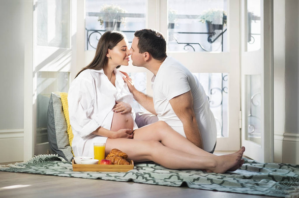 Pregnant woman and man having breakfast with orange juice near w - Photo, Image