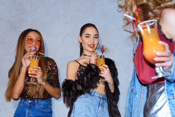tiro cortado de mulheres multiétnicas na moda bebendo coquetéis na festa
 - Foto, Imagem