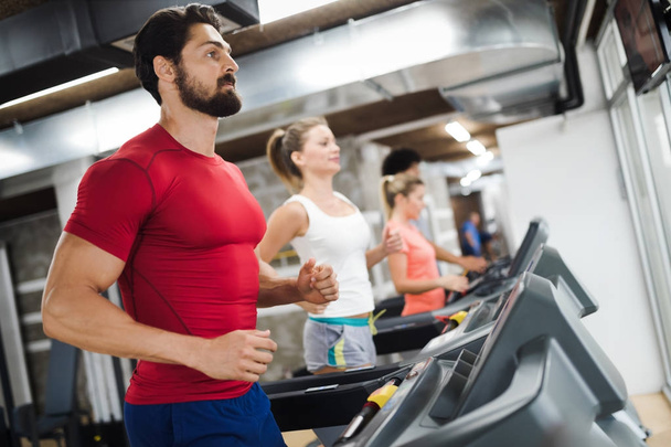 Young handsome man doing cardio training on treadmill in gym - Фото, зображення