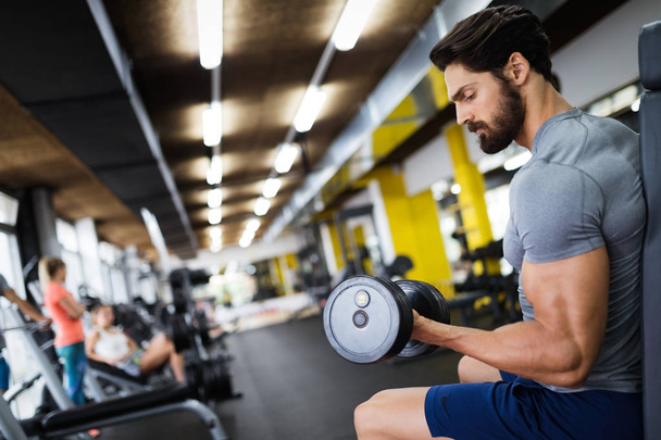 Determined male working out in gym lifting weights - Photo, Image
